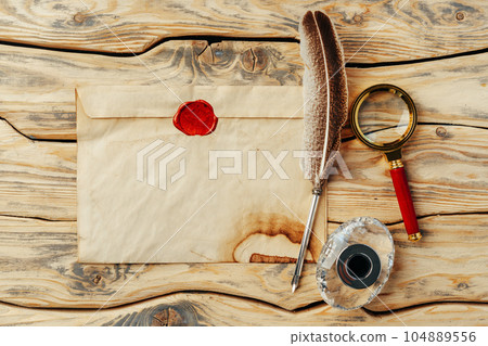 Old paper on brown wood background with feather 104889556