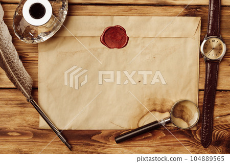 Old paper on brown wood background with feather 104889565