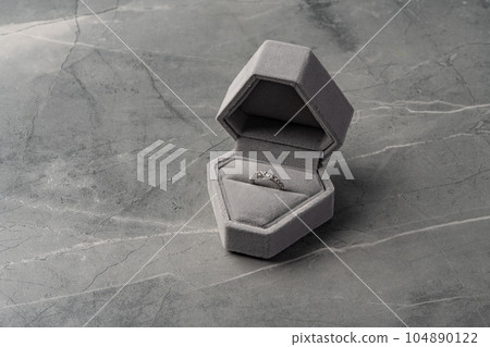 Golden ring in jewelry box on gray background 104890122