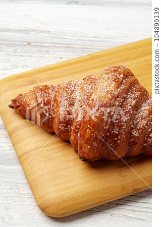 Freshly baked croissant with powdered sugar on wooden board 104890139