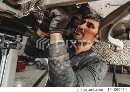 Auto mechanic repairs running gear of a car in car service 104890454