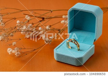 Golden ring in jewelry box on orange background Golden ring in jewelry box on orange background 104890650