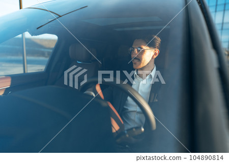 Young businessman in elegant suit driving luxury car Young businessman in elegant suit driving luxury car 104890814