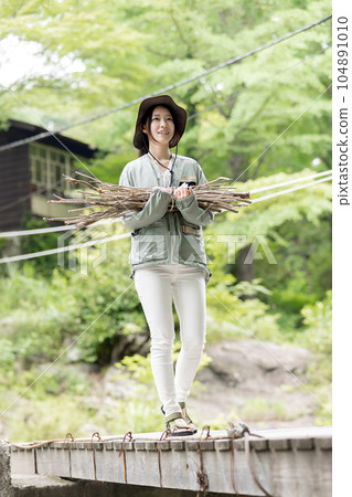 一名婦女在營地裡搬運木柴(樹枝) 一名婦女在營地裡搬運木柴(樹枝) 104891010