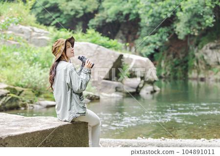 A woman enjoying bird-watching on the riverbed A woman enjoying bird-watching on the riverbed 104891011