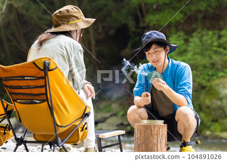 A man puts on a mosquito-repellent incense at a riverside camp A man puts on a mosquito-repellent incense at a riverside camp 104891026