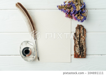 Blank letter, dry flowers and antique feather pen on wooden background Blank letter, dry flowers and antique feather pen on wooden background 104891111