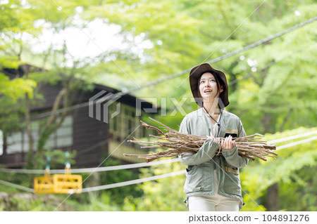 一名婦女在營地裡搬運木柴（樹枝） 104891276