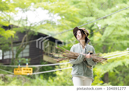 一名婦女在營地裡搬運木柴（樹枝） 104891277