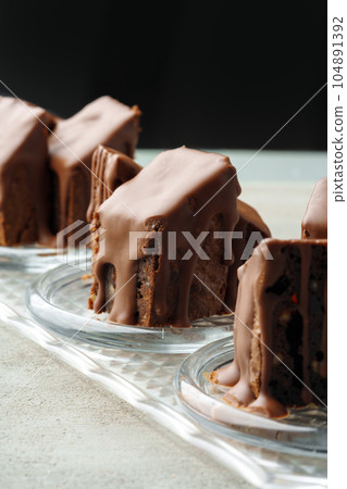 Chocolate sponge cake coated with chocolate sauce on glass plate Chocolate sponge cake coated with chocolate sauce on glass plate 104891392