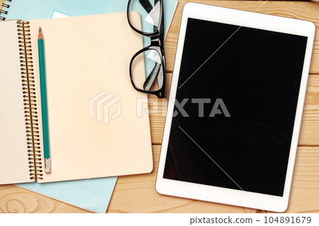 Top view of wooden table with white digital tablet with black screen on it 104891679