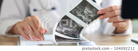Female doctor with stethoscope doing paperwork, checking medical documents at workplace. Female doctor with stethoscope doing paperwork, checking medical documents at workplace. 104892212