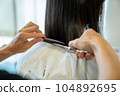 Woman getting a haircut at a beauty salon 104892695