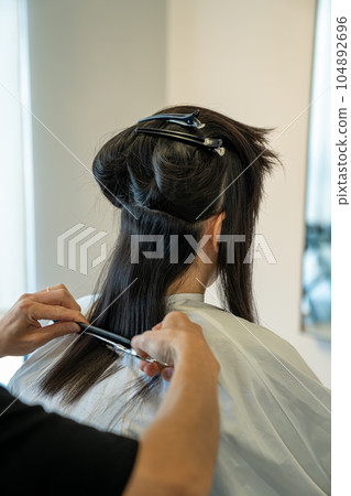 Woman getting a haircut at a beauty salon 104892696