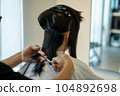 Woman getting a haircut at a beauty salon 104892698