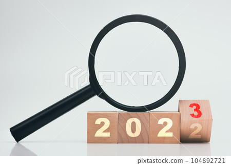 2023 wood block with magnifying glass on white background. 104892721