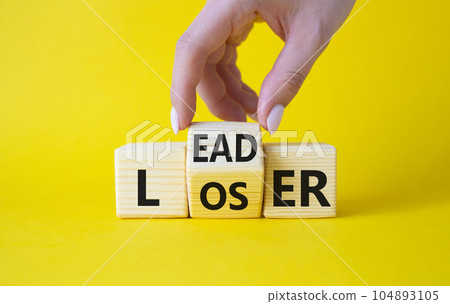 Leader vs Loser symbol. Businessman hand turns wooden cubes and changes the word Loser to Leader. Beautiful yellow background. Leader vs Loser and business concept. Copy space Leader vs Loser symbol. Businessman hand turns wooden cubes and changes the word Loser to Leader. Beautiful yellow background. Leader vs Loser and business concept. Copy space 104893105