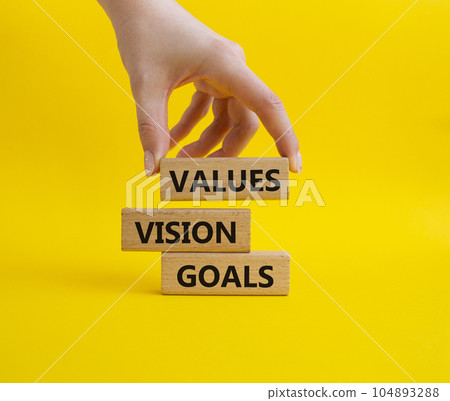 Values Vision Goals symbol. Concept words Values Vision Goals on wooden blocks. Beautiful yellow background. Busimessman hand. Business and Values Vision Goals concept. Copy space. 104893288