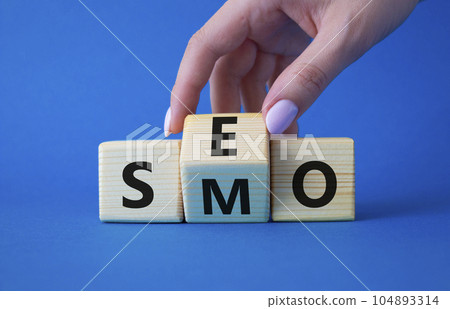 SEO vs SMO symbol. Businessman hand turns wooden cubes and changes the word SMO to SEO. Beautiful blue background. SEO vs SMO and business concept. Copy space SEO vs SMO symbol. Businessman hand turns wooden cubes and changes the word SMO to SEO. Beautiful blue background. SEO vs SMO and business concept. Copy space 104893314