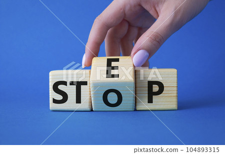Step vs Stop symbol. Businessman hand turns wooden cubes and changes the word Stop to Step. Beautiful blue background. Step vs Stop and business concept. Copy space Step vs Stop symbol. Businessman hand turns wooden cubes and changes the word Stop to Step. Beautiful blue background. Step vs Stop and business concept. Copy space 104893315