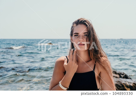 Woman summer travel sea. Happy tourist in hat enjoy taking picture outdoors for memories. Woman traveler posing on the beach at sea surrounded by volcanic mountains, sharing travel adventure journey Woman summer travel sea. Happy tourist in hat enjoy taking picture outdoors for memories. Woman traveler posing on the beach at sea surrounded by volcanic mountains, sharing travel adventure journey 104893330