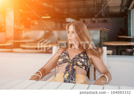 Happy woman portrait in cafe. Boho chic fashion style. Outdoor photo of young happy woman with long hair, sunny weather outdoors sitting in modern cafe. Happy woman portrait in cafe. Boho chic fashion style. Outdoor photo of young happy woman with long hair, sunny weather outdoors sitting in modern cafe. 104893332