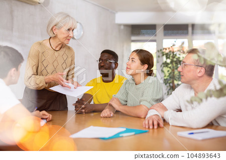 Group of multinational people discussing documents at table 104893643