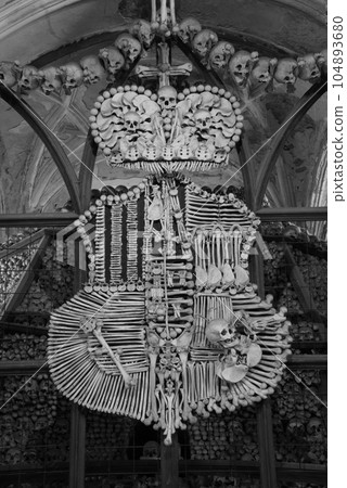 Grayscale shot of an art sculpture made of human bones in the Sedlec Ossuary in Kutna Hora, Czech Republic 104893680