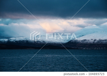 Waterscape with snow-covered mountains on the fjord shore near Tromso, Norway 104893723