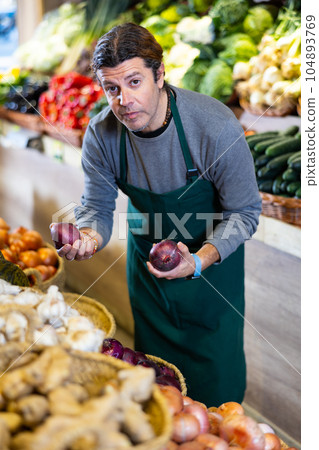 Adult man selling onions in shop Adult man selling onions in shop 104893769