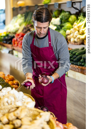 Adult man selling onions in shop 104893786