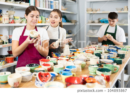 Two young women examining pottery in workshop Two young women examining pottery in workshop 104893867