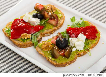 Toasts with guacamole, fresh vegetables, feta cheese 104893906