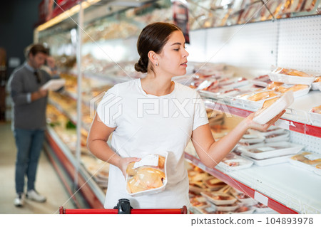 Woman looking for packaged chicken in grocery store Woman looking for packaged chicken in grocery store 104893978