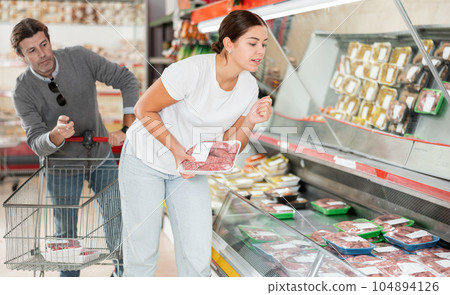 Married couple choosing meat together in the meat department of supermarket 104894126