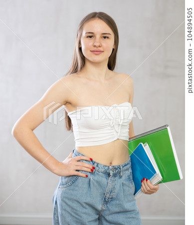 Young woman with stack of notebooks posing in studio 104894505