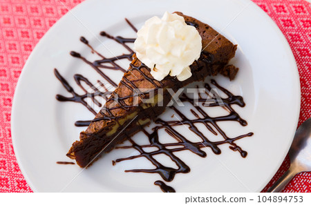 Tasty brownie cake served with butter cream and dark chocolate at plate 104894753