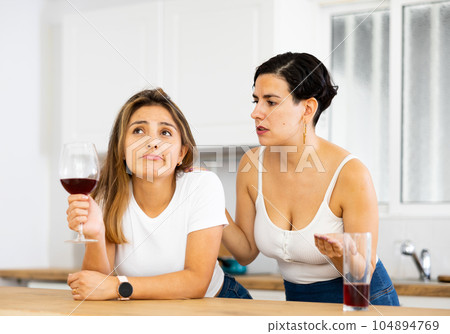 Woman consoling the depressed woman at table in kitchen 104894769