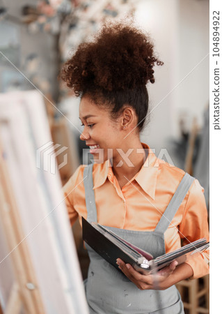 Beautiful American African artist woman painting in art studio at the university classroom Beautiful American African artist woman painting in art studio at the university classroom 104894922
