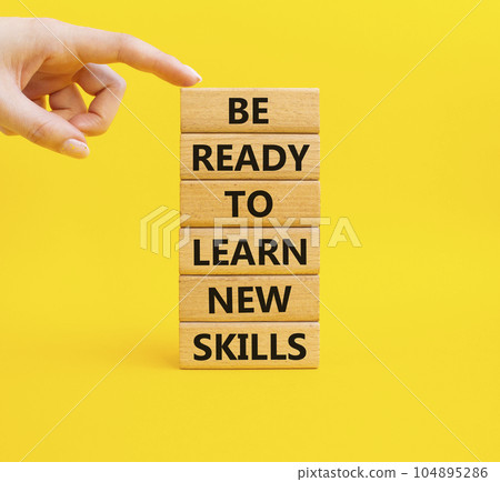 Learn new skills symbol. Concept words Be ready to Learn new skills on wooden blocks. Beautiful yellow background. Businessman hand. Business and Learn new skills concept. Copy space. 104895286