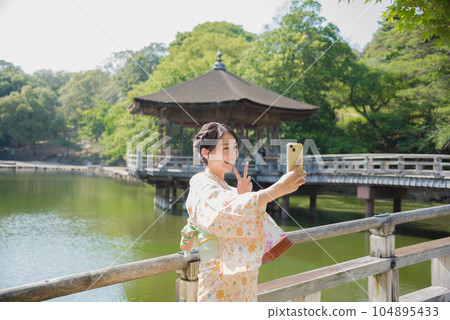 Kimono woman taking a smartphone selfie at a tourist spot Kimono woman taking a smartphone selfie at a tourist spot 104895433