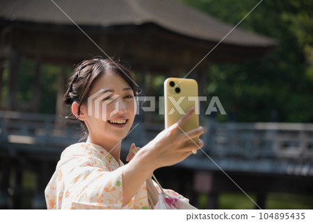 和服女子在旅遊景點用智能手機自拍 和服女子在旅遊景點用智能手機自拍 104895435