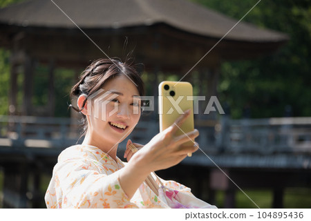 和服女子在旅遊景點用智能手機自拍 和服女子在旅遊景點用智能手機自拍 104895436