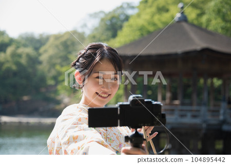Kimono woman taking a V-log selfie at a tourist spot 104895442