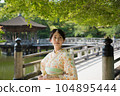 A smiling kimono woman standing in a fresh green tourist spot 104895444