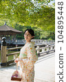 A smiling kimono woman standing in a fresh green tourist spot 104895448