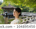 A smiling kimono woman standing in a fresh green tourist spot 104895450