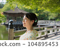 A smiling kimono woman standing in a fresh green tourist spot 104895453
