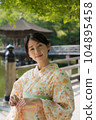 A smiling kimono woman standing in a fresh green tourist spot 104895458
