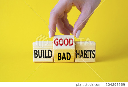 Build Good or Bad Habits symbol. Businessman hand turns wooden cubes and changes the words Build Bad Habits to Build good Habits. Beautiful yellow background. Business concept. Copy space 104895669